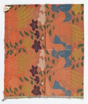  A textile sample featuring a coral-orange background with a subtle textured pattern, overlaid with stylized blue and brown leaves, as well as pale beige to soft purple floral motifs.