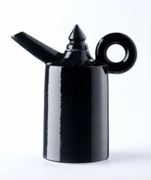  A black, glossy coffee pot with a cylindrical body and an exaggerated circular handle, set against a white-to-light-gray gradient background. The pot's modern design is characterized by a reflective surface and bold, geometric shapes.