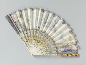  A delicate antique hand fan displayed partially open. It has dark guard sticks with a golden detail, golden fan sticks, and a light fabric with soft blue and lavender shades embellished with faded botanical designs.