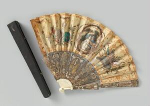  Antique folding fan with intricate designs, including a circular portrait and floral patterns on a light, aged background, displayed next to its black protective case on a neutral gray surface. The fan exhibits a blend of soft natural tones with touches of green, red, and blue, while the case provides a contrasting solid dark hue.