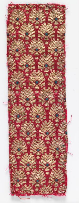  A digital image of a narrow, elongated textile featuring a symmetrical and repetitive pattern of stylized floral motifs in shades of red, gold, orange, green, and blue, with an overall rich, decorative appearance.