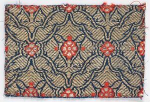  Intricately patterned fabric with a beige background featuring a repeating design of red floral motifs with yellow centers and a surrounding lattice of dark blue feathery shapes with white and yellow-green highlights.