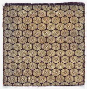  An image of a square textile with a repetitive hexagonal pattern in dark brown and beige tones, featuring a radial floral motif at the center of each hexagon, and small, bright motifs against a textured background.