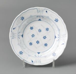 
 A round, feldspar porcelain plate designed by Gerhard Munthe titled "Blaaveis," featuring hand-painted and stencil-painted underglaze decorations in cobalt blue which depict snowflake-like motifs in the center, with a scalloped design in the well and a series of similar floral patterns around the rim against a glossy white background.