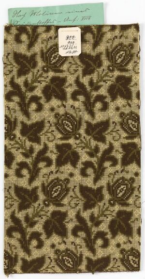  A swatch of fabric or paper with a dark brown and beige floral pattern and a muted green label at the top with handwritten text and numbers.