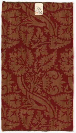  An image of an ornate, floral-patterned fabric predominantly in shades of deep red, with a white rectangular label in the upper right corner.