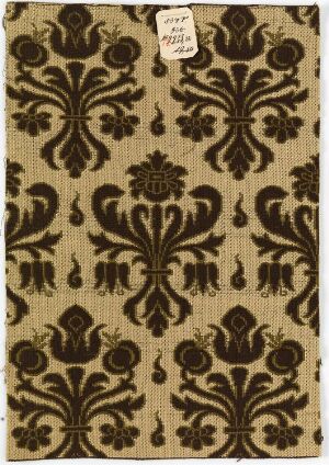  A photograph of an ornate brown pattern on a beige background reminiscent of classic wallpaper or textile designs, with a white tag at the top bearing handwritten text, the specifics of which are indiscernible.