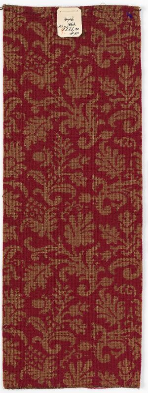  A rectangular piece of deep maroon fabric with a darker maroon intricate floral pattern, featuring a white label with text at the top.