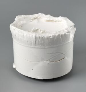  "Gjennom" - a white porcelain ceramic object by artist Jens Erland, featuring textured edges and a horizontal crack-like design, set against a grey background.