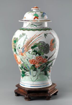  A white porcelain vase adorned with orange koi fish and green and pink botanical patterns, complete with a lid and resting on a dark wooden stand against a light grey background. Artist name and title are unknown.