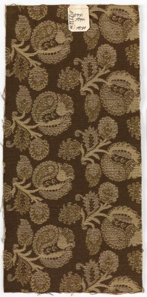  A photograph of a piece of fabric featuring a repeating pattern of stylized floral designs in a lighter shade on a dark brown background, with a small, unreadable label in the upper right corner.