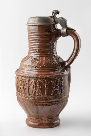  An antique brown ceramic jug with embossed figures on the lower half, a hinged metal lid, and a robust handle, set against a neutral background. Artist name and title are unknown.