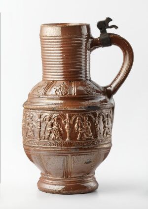  A terracotta pottery jug with decorative relief patterns on the body, a ribbed upper segment, a dark brown glossy handle, and a small metal spout fixture against a white background.