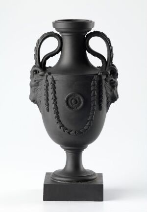  A black classic amphora vase with sculpted braided handles and raised circular and festoon decorative patterns, standing against a light grey background.