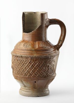  A historical ceramic jug with intricate geometric patterns and a robust handle, predominantly in terracotta hues, displayed against a neutral background.