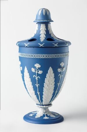  A decorative cobalt blue urn with a lid, adorned with white botanical motifs and geometric patterns, evoking a classic and elegant style, set against a light neutral background. Artist name and title are unknown.