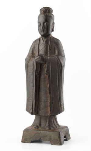  An antique metal statue of a robed figure standing with hands clasped in front, possible religious or philosophical significance, detailed with a serene facial expression and traditional headgear, colored in shades of dark brown and gray with a greenish patina. Artist name and title are unknown.