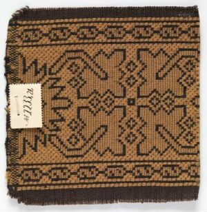  A square textile sample with frayed edges, featuring an intricate symmetric geometric pattern in tan and brown colors, with a white inventory tag labeled "1931.33" in the bottom left corner.