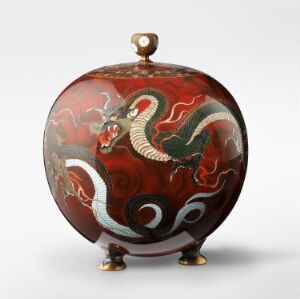  A spherical, ornate container with three small golden legs, featuring an intricately painted white and light blue dragon on a marbled deep red background with green scale accents and swirling smoke patterns.