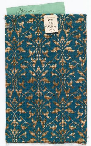  A patterned fabric swatch with a dark turquoise background and a golden tan floral motif, accented with light blue details, partially covered by a white label in the upper right corner.