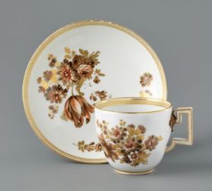  An ornate porcelain tea cup and matching saucer with a white background, embellished with a hand-painted floral design in oranges, browns, and greens, finished with gold trim along the edges.