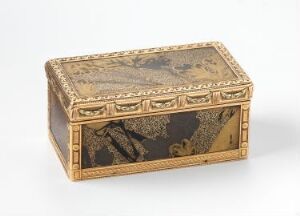  An antique, rectangular trinket box with elaborate cream, gold, and brown landscapes and structures depicted on its surfaces, and gilded metal accents on its edges and corners, against a plain light background.