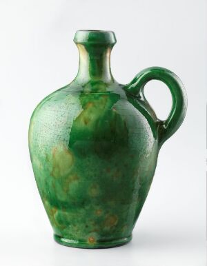  A ceramic jug with a rich green glaze showing darker variegated patterns, featuring a rounded body, a graceful handle, and set against a neutral background. Artist name and title are unknown.