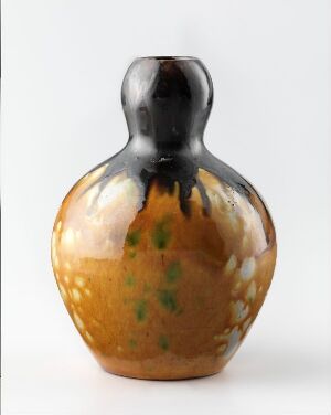  A rounded vase with a marbled glaze, featuring a warm amber base with spots of green, transitioning to a glossy black at the narrow neck and opening.