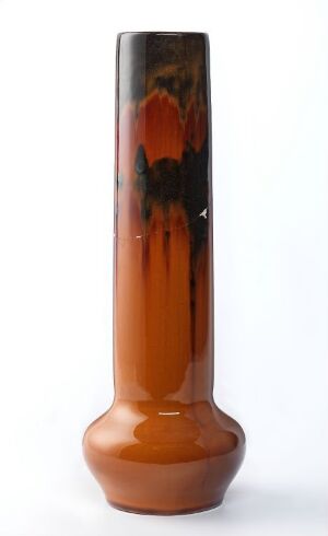 
 An elongated, tapering vase with a glossy finish, featuring a burnt orange base transitioning into a darker brown with black and deep red streaks flowing down from the top.