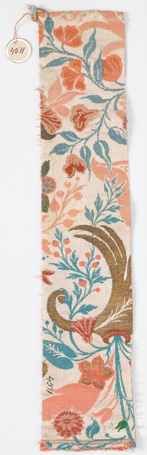  A vertical strip of fabric featuring a vintage floral pattern with red-orange flowers, light teal leaves, and golden-brown accents on a pale creamy background.