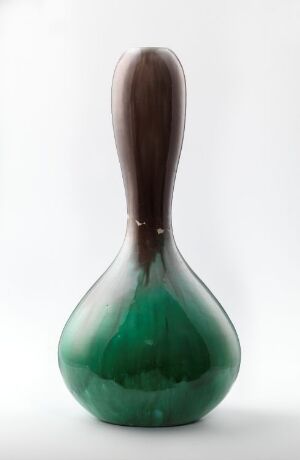  A bulbous, gourd-shaped glass object with a wide, rounded emerald green base transitioning to a smoky brown neck, set against a light background.