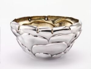  An artful metal bowl with a silver exterior and gold interior, featuring an irregular, organic shape and a reflective polished surface.