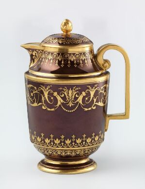  An ornate deep purple teapot with golden embellishments, featuring scrollwork and floral patterns, stands against a neutral off-white background. The gold-handled lid and spout accentuate its elegance.