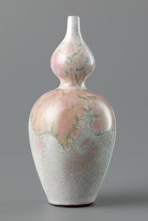  An elegant ceramic vase with a tapered neck and rounded body, featuring soft speckled texture with subtle washes of pink, green, and blue hues, against a neutral grey background.