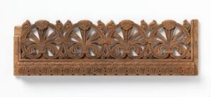  A long and narrow wooden carved panel featuring a symmetrical and repeating floral pattern with detailed petals and interconnected foliage, exhibiting warm brown tones and textural depth.