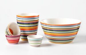  A collection of turned and glazed porcelain tableware with colorful horizontal stripes, designed by Alfredo Häberli, displayed against a white background.