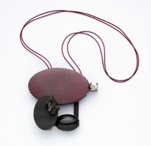  Artistic necklace titled "Dark of Night" by Anne Léger, featuring an oval-shaped dark red-brown wooden pendant with attached glossy black obsidian and metallic pyrite pieces, held by a burgundy cord, on a white background.