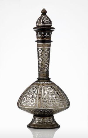  An ornate, metallic gray vessel with a bulbous base and a slim, tall neck topped with a dome-shaped lid with a sharp finial, showcasing intricate etched patterns, set against a plain off-white background.