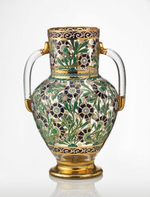  An intricately designed vase with a floral pattern in green, purple, blue, and gold, with curved handles and a golden base, against a plain background.