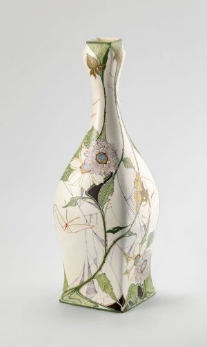  A slender, elongated ceramic vase with a painted botanical design featuring green leaves and pastel-colored flowers on a soft white background. The vase has an organic shape that tapers into a narrow neck.