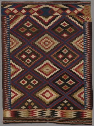  An intricately patterned, handmade textile featuring repeating diamond shapes in a rich color palette of navy blue, burgundy, dark brown, and cream. The geometric patterns are accented by a detailed border, alluding to traditional crafting techniques.