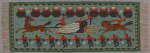  "Kongen drar forbi" by Den Norske Husflidsforening - Wool textile artwork displaying a stylized royal procession with horses, a white and gray chariot, and figures in red uniforms, set against an aquamarine background framed by a darker teal border with red and turquoise details.