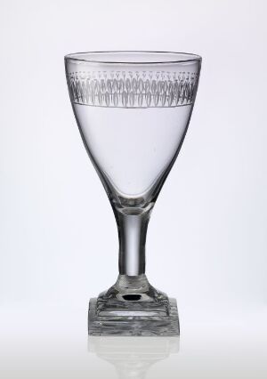  A transparent glass with a wide, cone-shaped bowl with diamond-patterned etching, a short stem, and a square base, against a stark white background. Artist name and title are unknown.