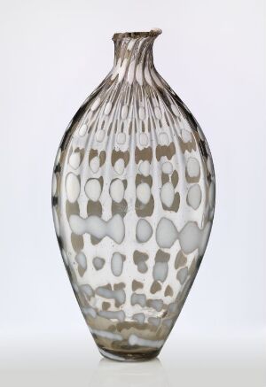  A tall glass vase with a narrow base and neck, and a wider midsection, featuring a pattern of muted taupe spots on a translucent white background, which gives the vase a glowing appearance. The vase stands against a plain, light background.