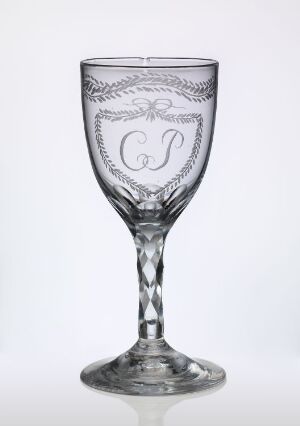  An intricately etched, crystal wine glass with a helical stem pattern and a monogram of the letters "G" and "S" in the center of the bowl, set against a plain white background.