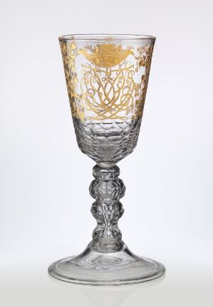  An intricate goblet with gold decorative patterns on the cup; the stem is elaborately molded, and the base is simple yet sturdy, set against a white background. Artistname and title are unknown.