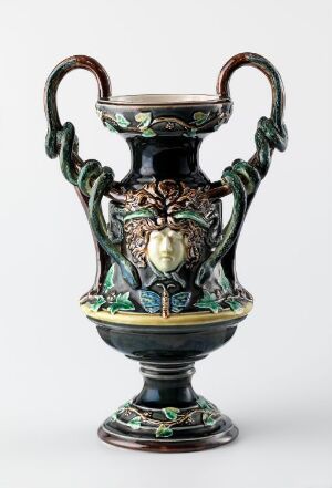  An intricately designed ceramic urn with a glossy forest green background, highlighted by gold and cream decorative elements, serpentine handles, and a central medallion featuring a classical facial profile.