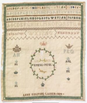  Antique embroidery sampler with alphabets and decorative motifs, featuring a central vine wreath with a phrase, initials "AL" and "ML," and creator's name "ANNE KRISTINE LASSEN - 1842" on a cream background with frayed edges.