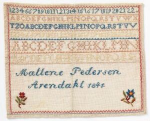  A traditional embroidered sampler featuring rows of red numbers and alphabets at the top with the name "Mallene Pedersen Arendahl 1844" stitched in dark blue in the center, and small colorful floral designs in the lower corners on an off-white fabric, framed by a red stitched border.