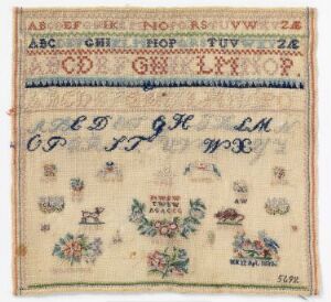  Antique embroidered sampler with multiple rows of alphabets at the top in different colors and styles, followed by a row of initials and a date in blue, and various detailed floral designs in a spectrum of colors on an aged cream fabric.